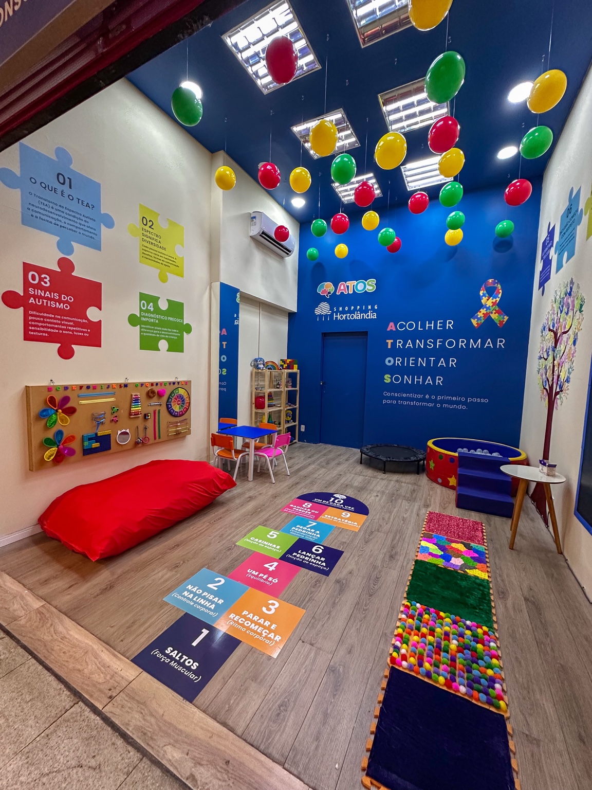 Interior da sala de regulação da Atos no Shopping Hortolândia, com recursos sensoriais, pufe e materiais de conscientização